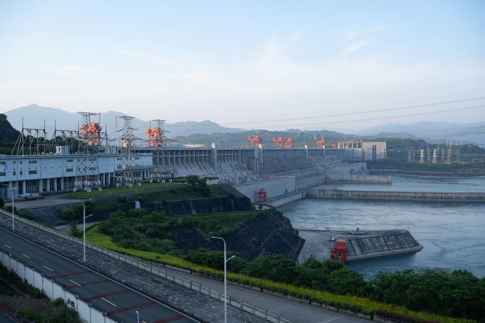 The Three Gorges Dam stretching across the Yangtze with the dam road and power lines in the foreground