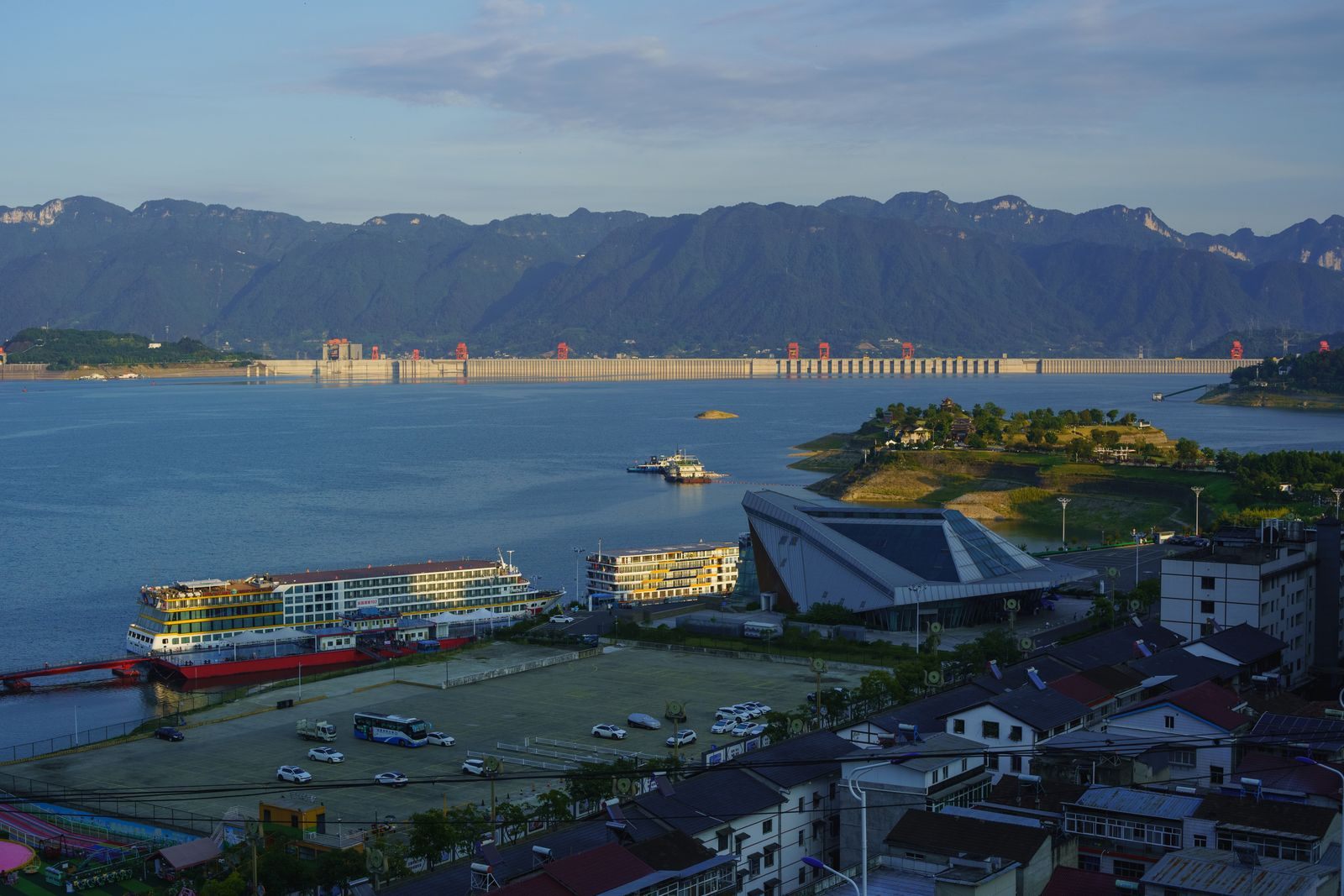Yangtze river cruise ships moored on the reservoir above the Three Gorges Dam, with the dam and mountains beyond